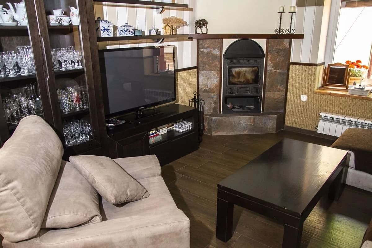Salón de Casa Las Parras con sofás, chimenea y vitrina