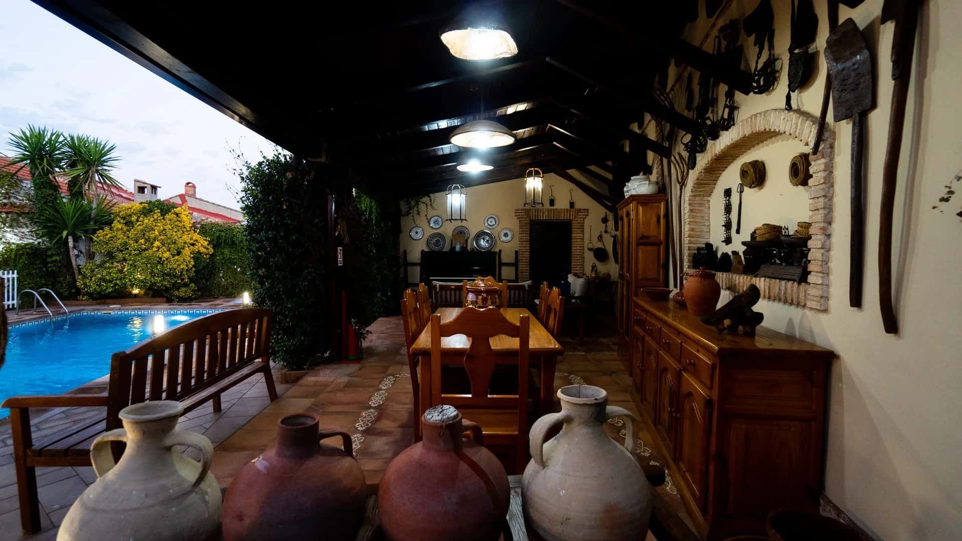 Porche de Casa Rural Tres Ventas al atardecer, con la mesa puesta y la piscina al fondo